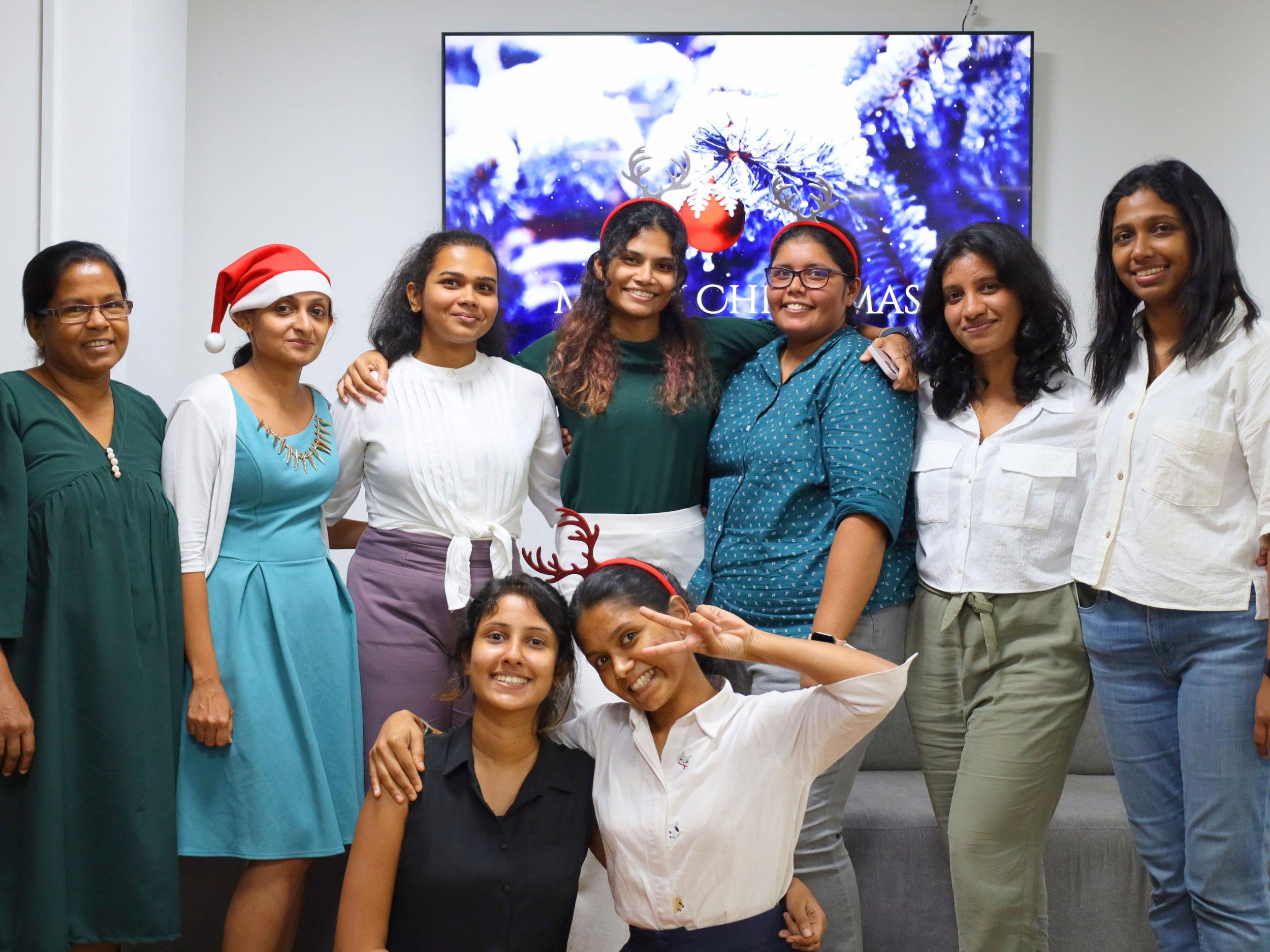 Group of female employees wearing Santa hats, smiling at the camera