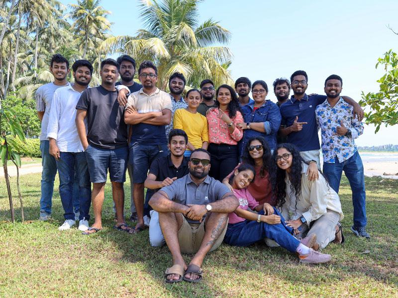 Team on a fun company outing at the beach, with coconut trees in the background