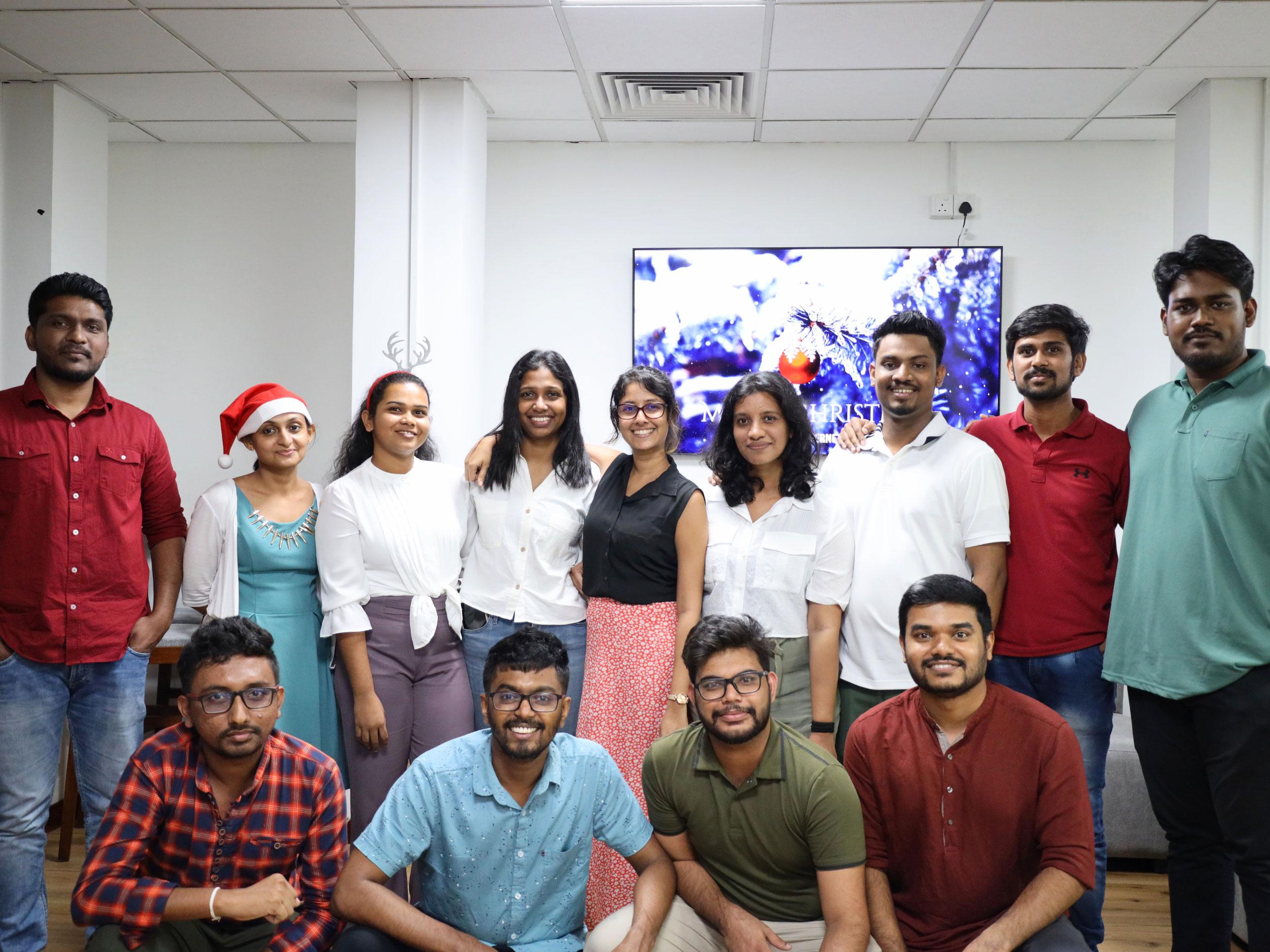 Group photo of company employees celebrating Christmas, wearing Santa hats