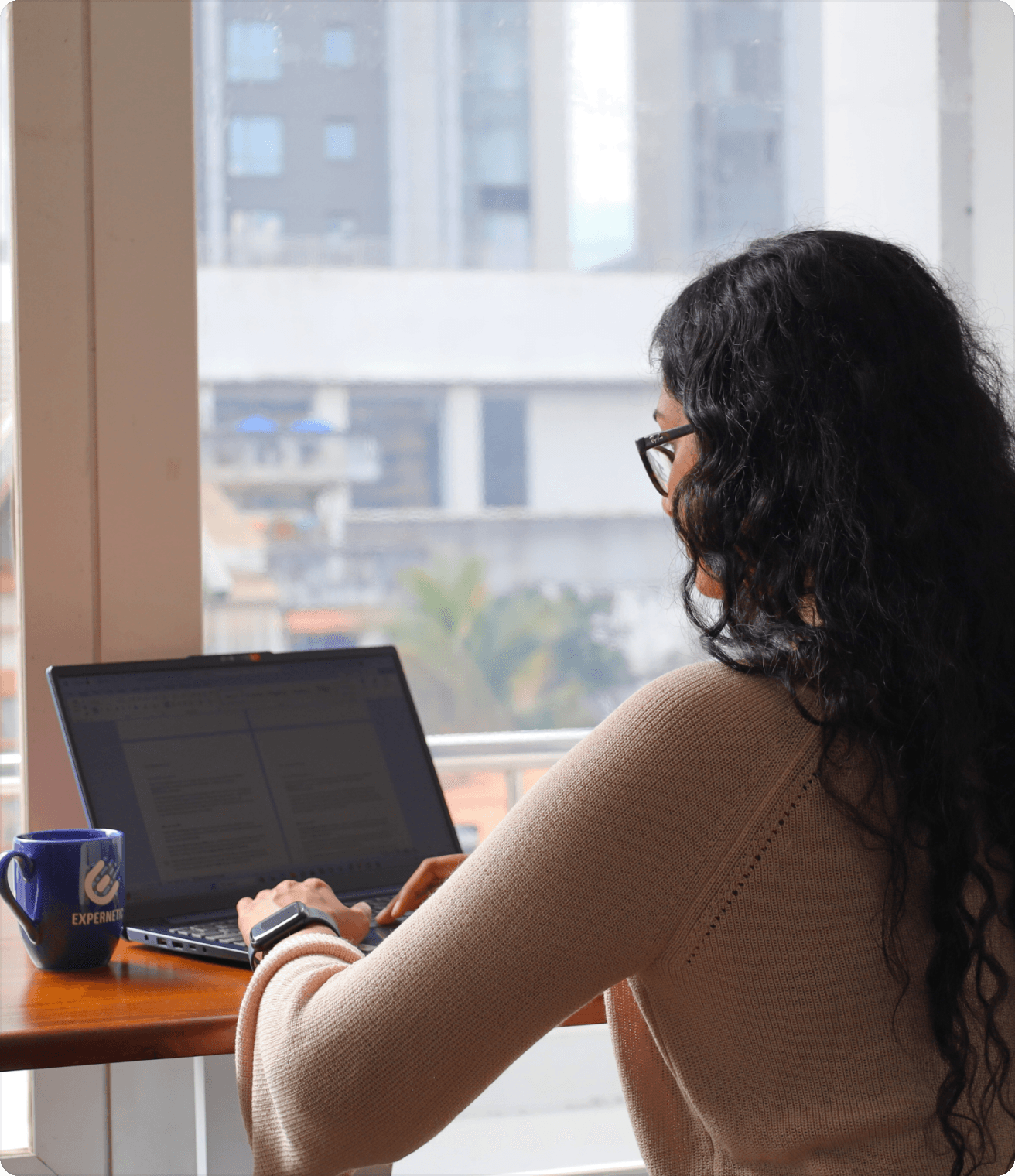 Employee working on laptop faced towards a window