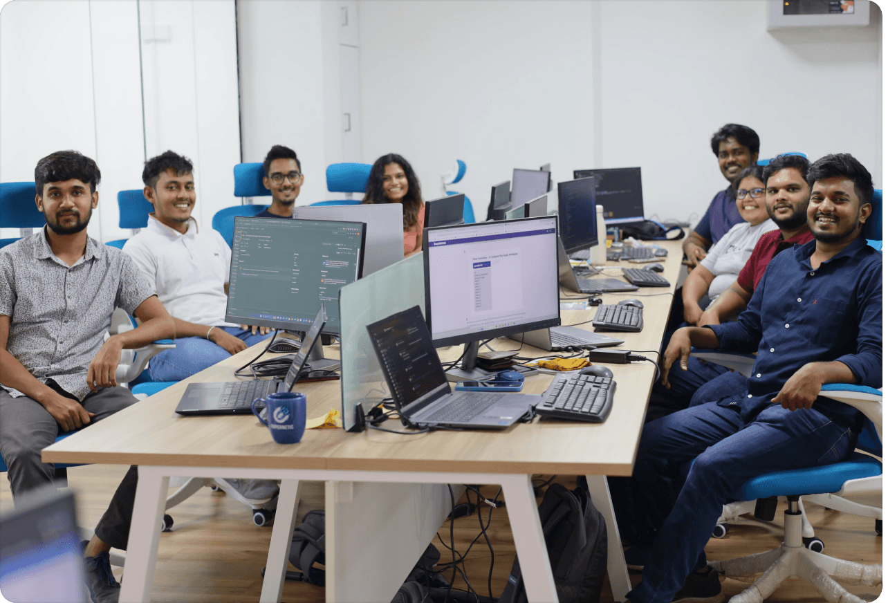 Employees at their desks, smiling at the camera 