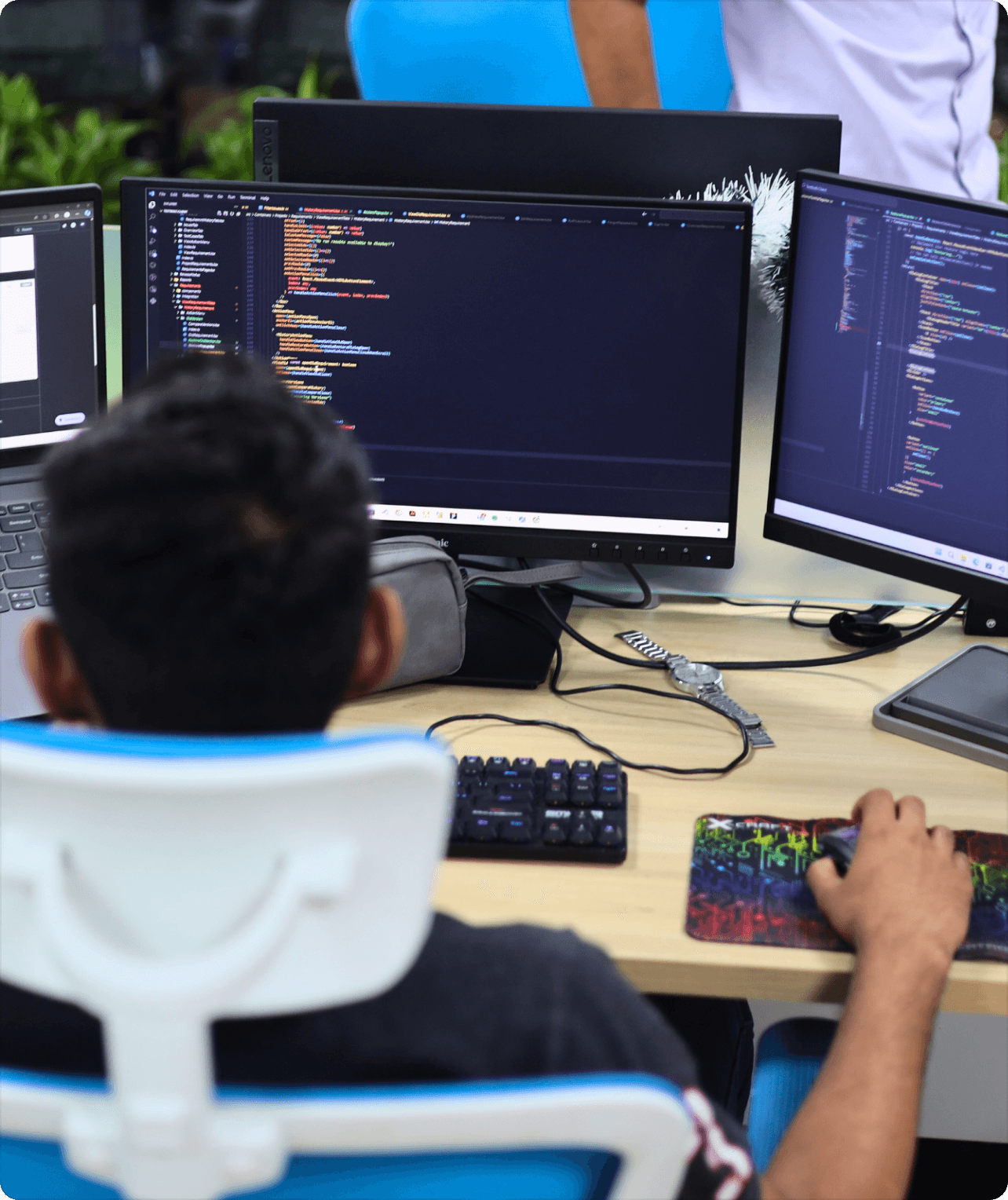 Programmer working on complex code with multiple monitors